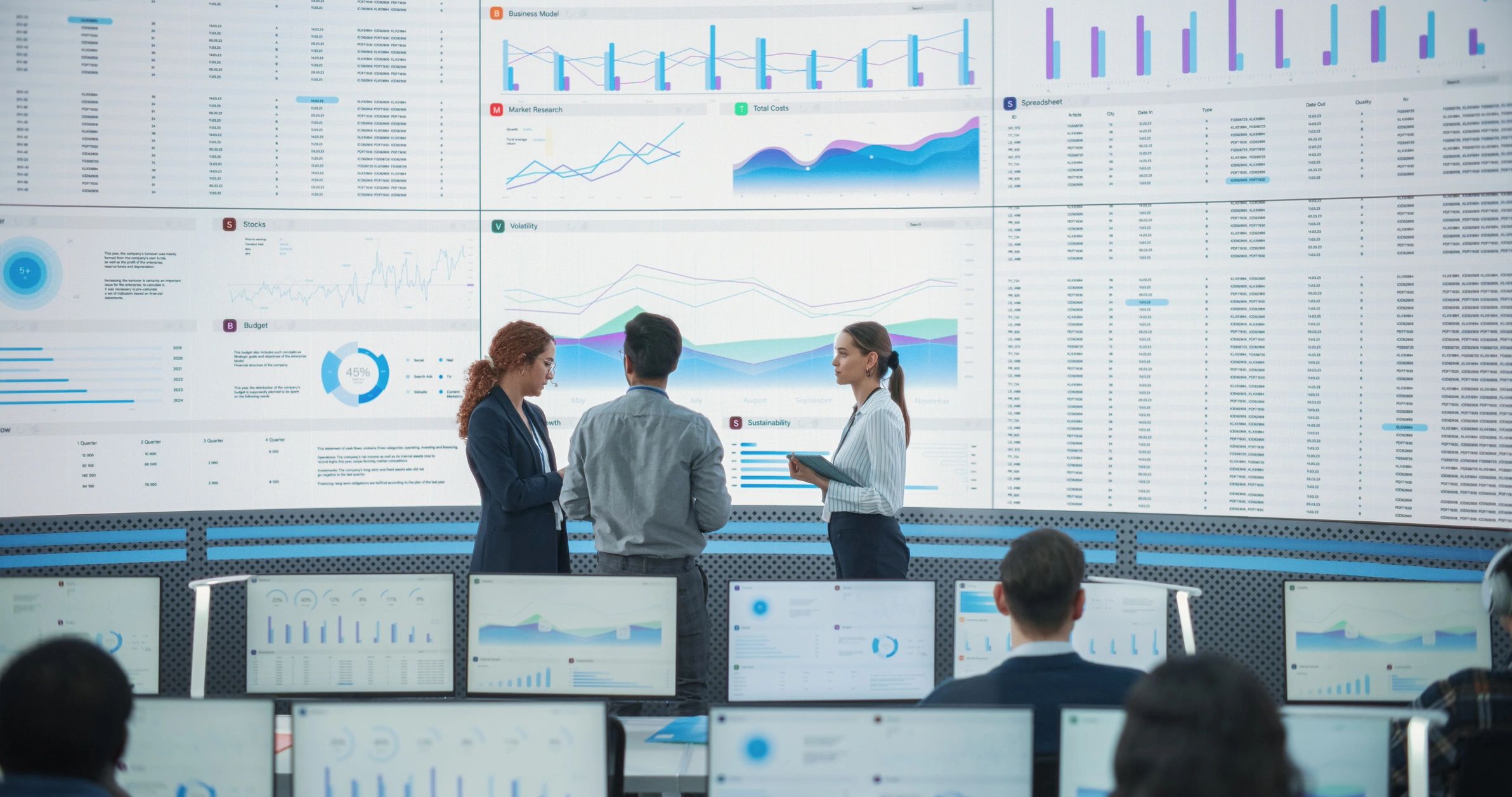 Diverse data team collaborating in front of a large analytics screen